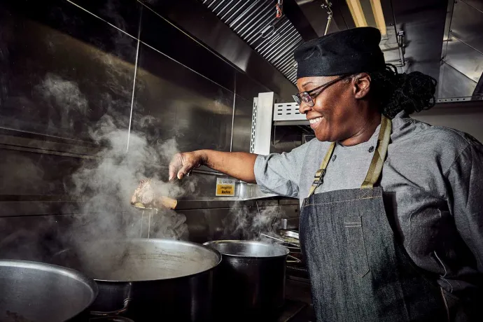 Elior's team chef cooking over a pot in the kitchen