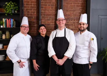 Diverse team of Elior North America chefs smiling together, representing our commitment to employee well-being, professional growth, and an inclusive workplace culture.