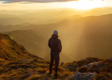 Person enjoying a peaceful mountain landscape at sunset, representing Elior North America’s commitment to physical and mental well-being, healthy lifestyles, and overall wellness.