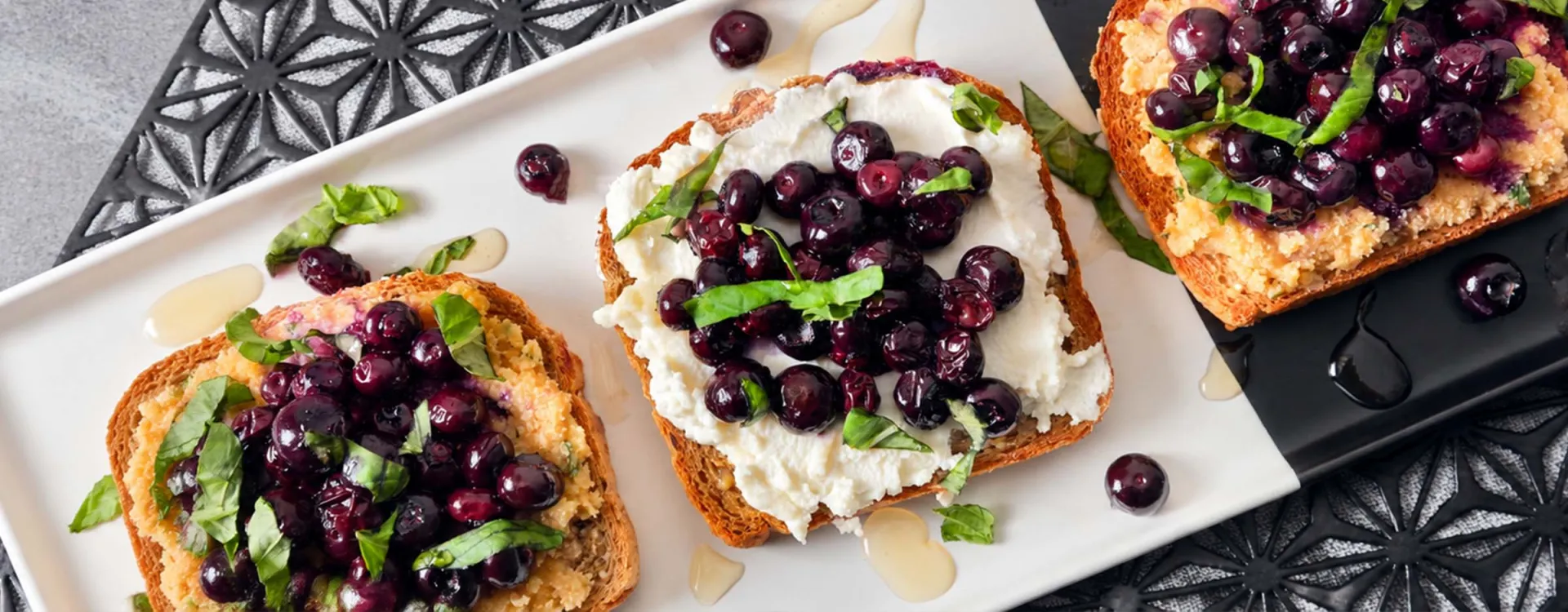 Fresh blueberry toast topped with creamy ricotta, basil, and honey, showcasing wholesome ingredients and nutritious dining options from Elior North America’s BeWell program.