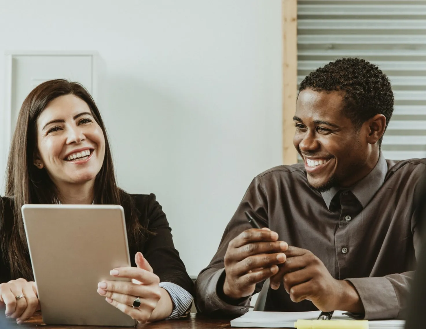 Co-workers overlooking at a tablet while smiling