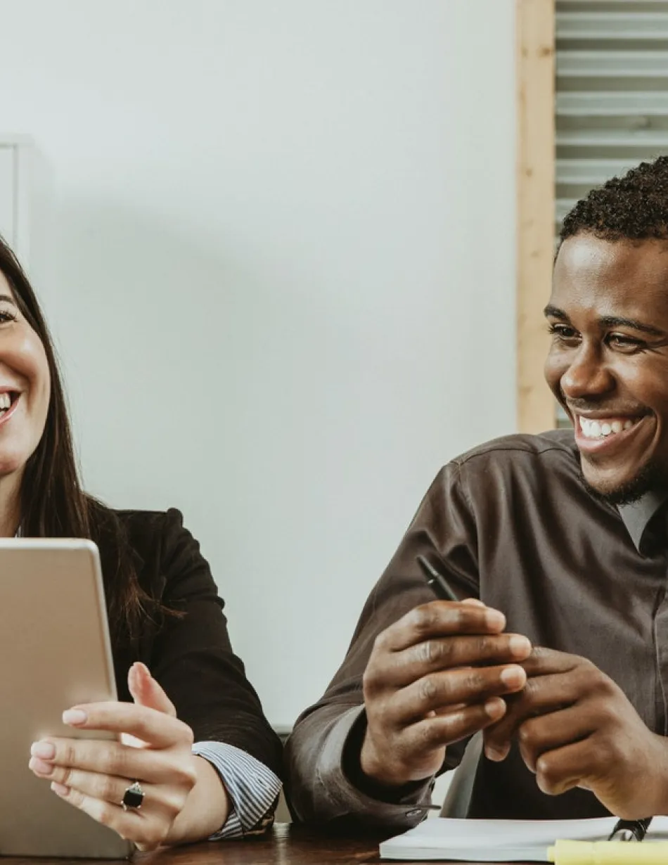 Co-workers overlooking at a tablet while smiling