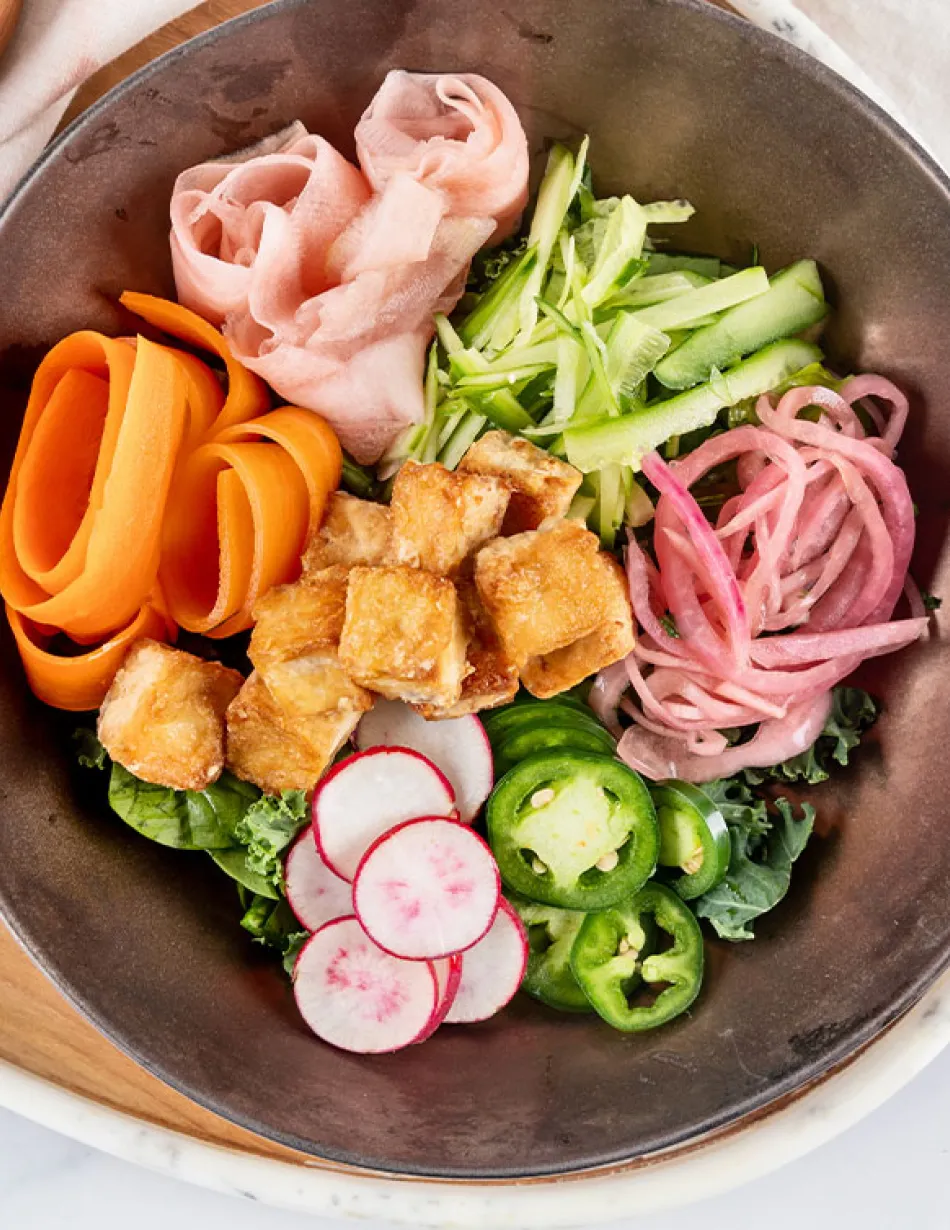 Overhead image of a dish comprised of pickled vegetables and fried tofu in a bowl