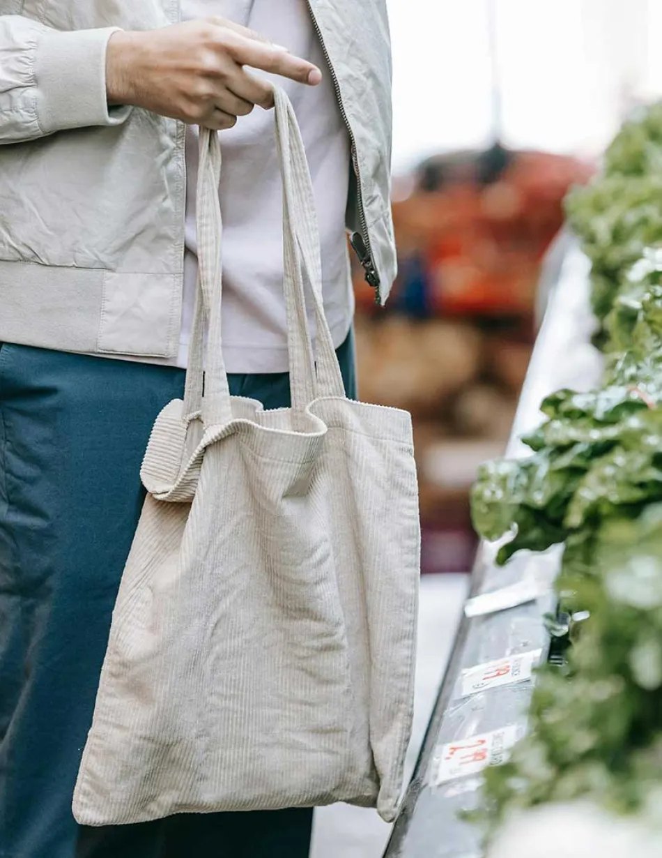 Person holding reusable bag standing in produce aisle