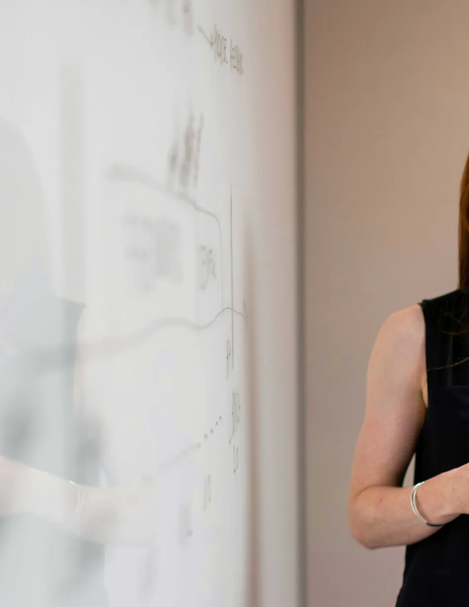 Office employee smiling while standing next to white board