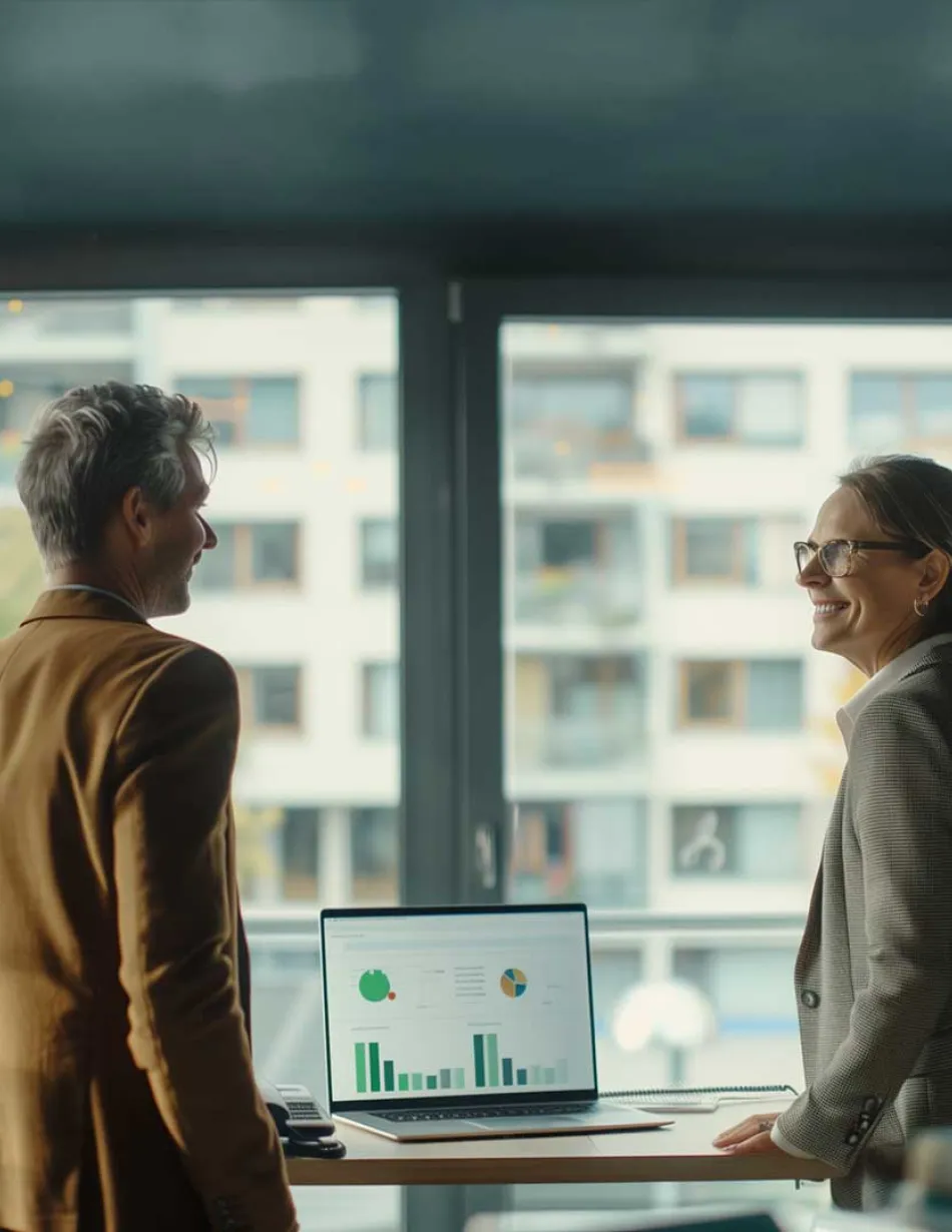 Two people overlooking report on laptop in office