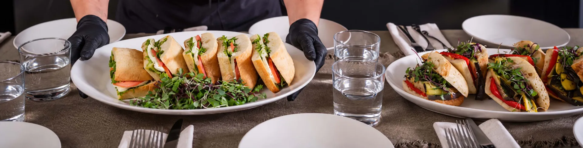 Elior North America culinary team member serves freshly prepared sandwiches and salads, showcasing quality food and hospitality.
