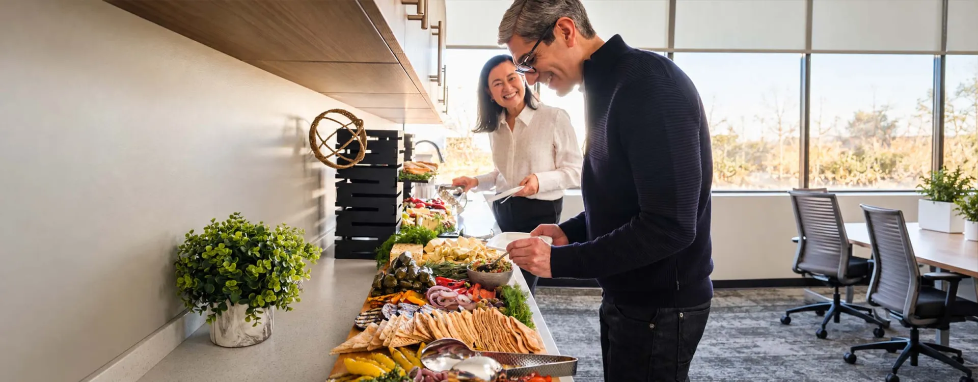 Guests enjoying a freshly prepared catered buffet featuring artisan cheeses, breads, and vegetables, showcasing Elior North America's corporate catering and event dining services.
