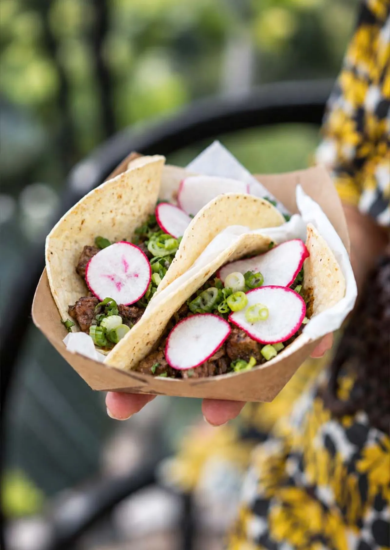 Two freshly prepared tacos topped with grilled meat, radishes, and green onions, showcasing Elior North America's culinary innovation and creative menu offerings.