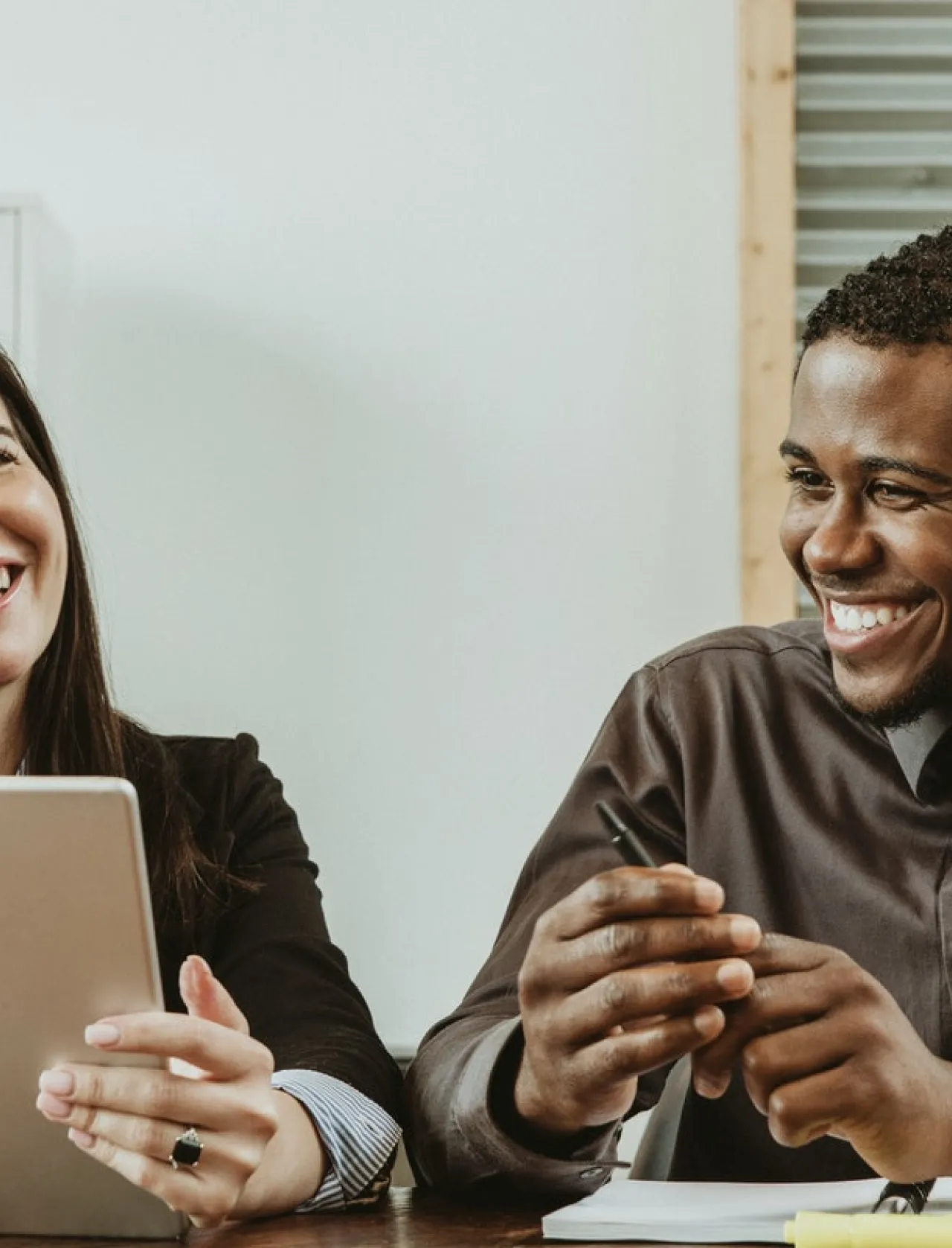Co-workers overlooking at a tablet while smiling